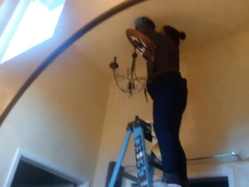 Electrician installing a chandelier in a Stratham residence